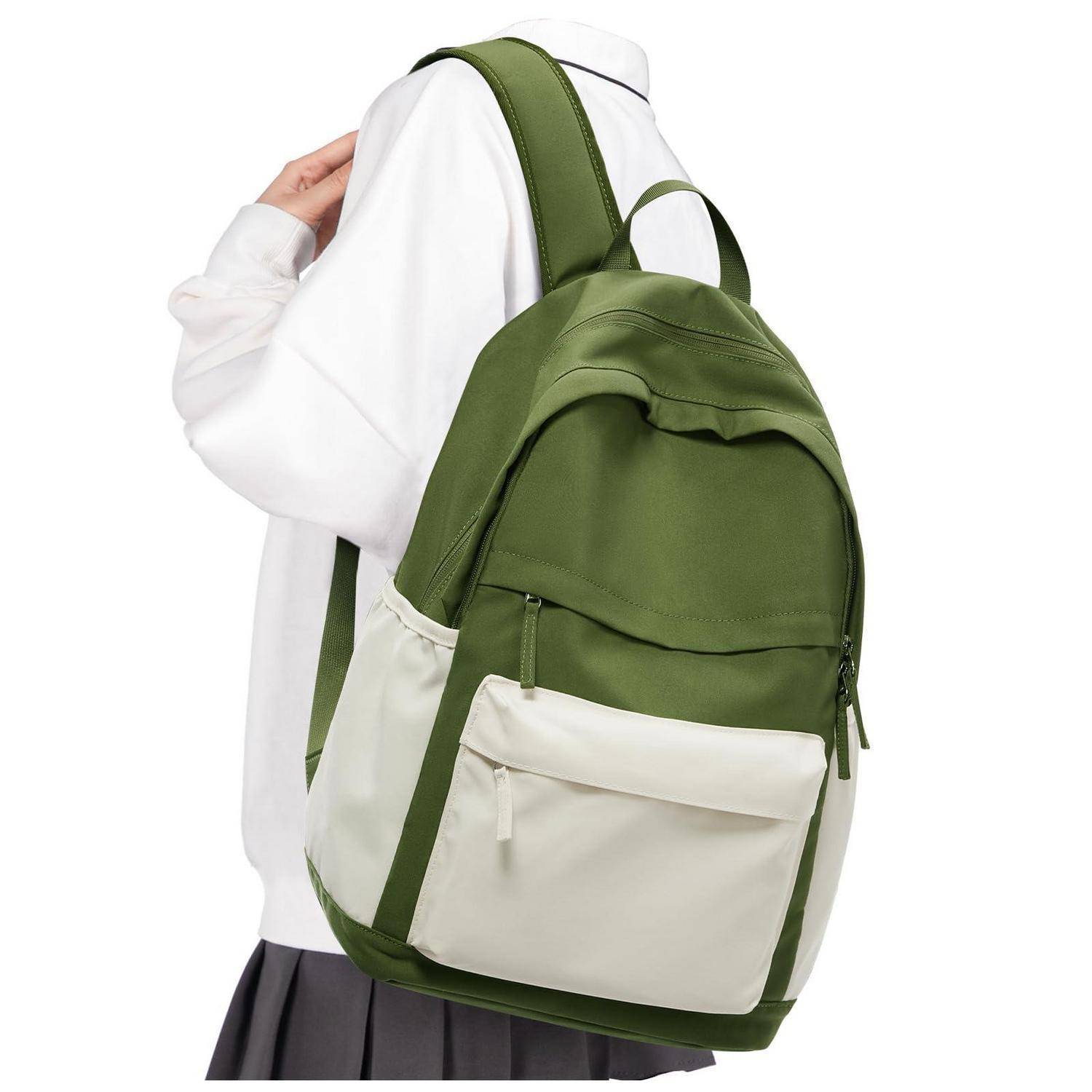 Person mit einem Rucksack in Olivgrün und Creme über einem weißen Hemd und einem dunklen Rock, von hinten vor einfachem Hintergrund gezeigt.