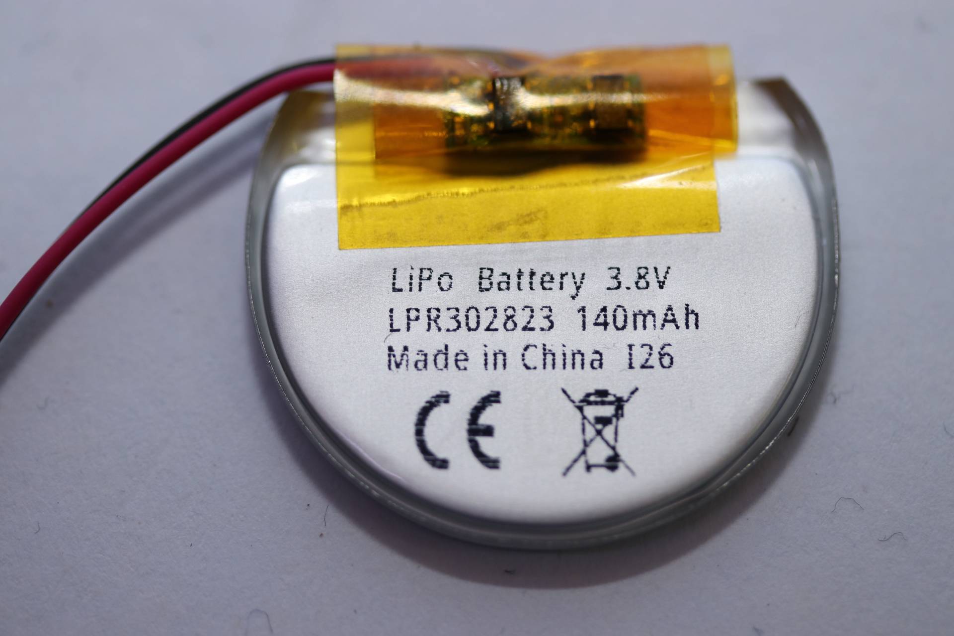 Nahaufnahme einer kleinen runden LiPo-Batterie mit der Beschriftung „LiPo Battery 3.8V LPR302823 140mAh