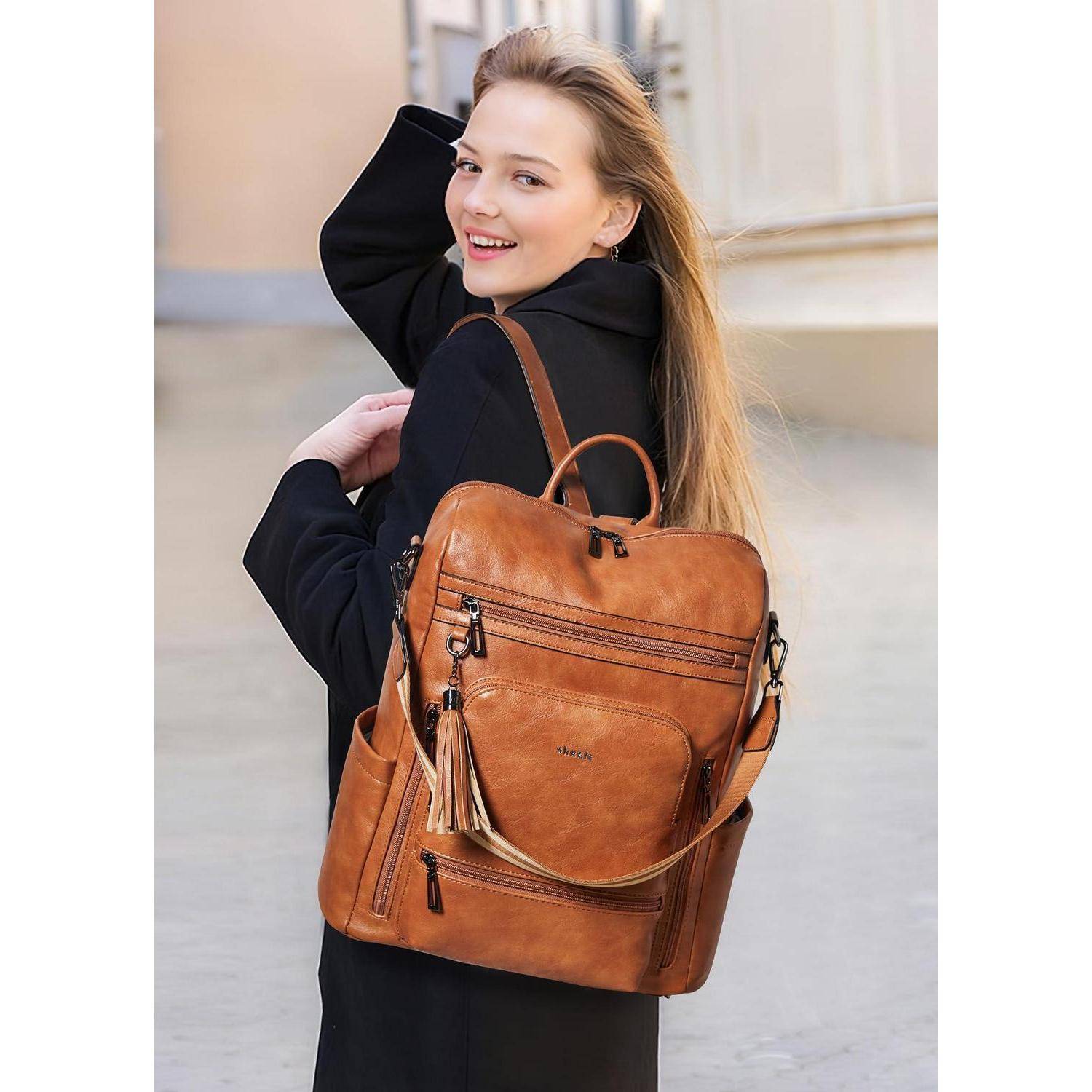 Lächelnde Frau in einem schwarzen Mantel, die einen beige Lederrucksack im Freien trägt.