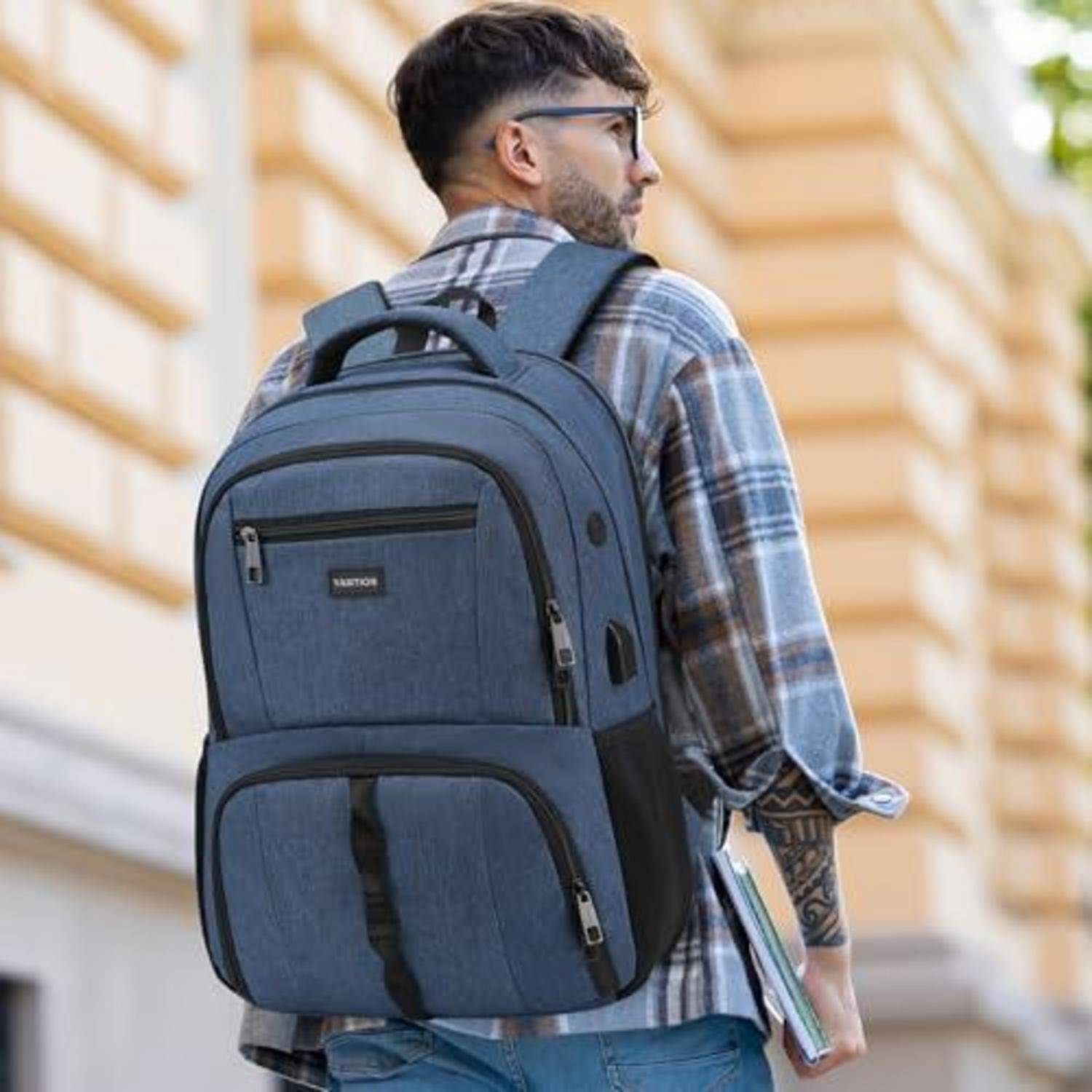 Ein Mann, der eine Brille und ein Karohemd trägt, trägt einen großen blauen Rucksack, während er draußen spaziert und Bücher in der Hand hält.