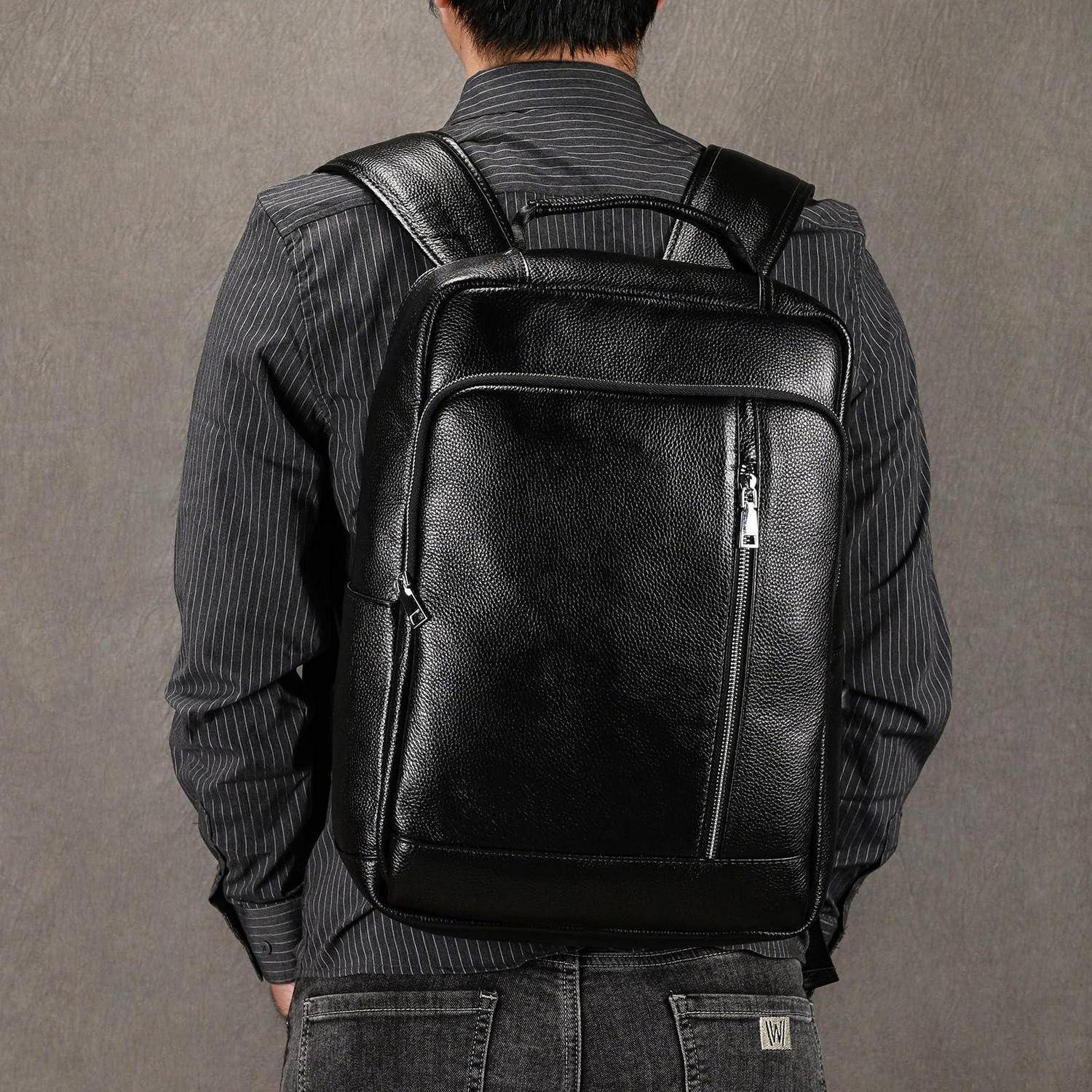 Mann mit schwarzem Lederrucksack über einem dunkelgestreiften Hemd, von hinten vor einem einfachen grauen Hintergrund gezeigt.