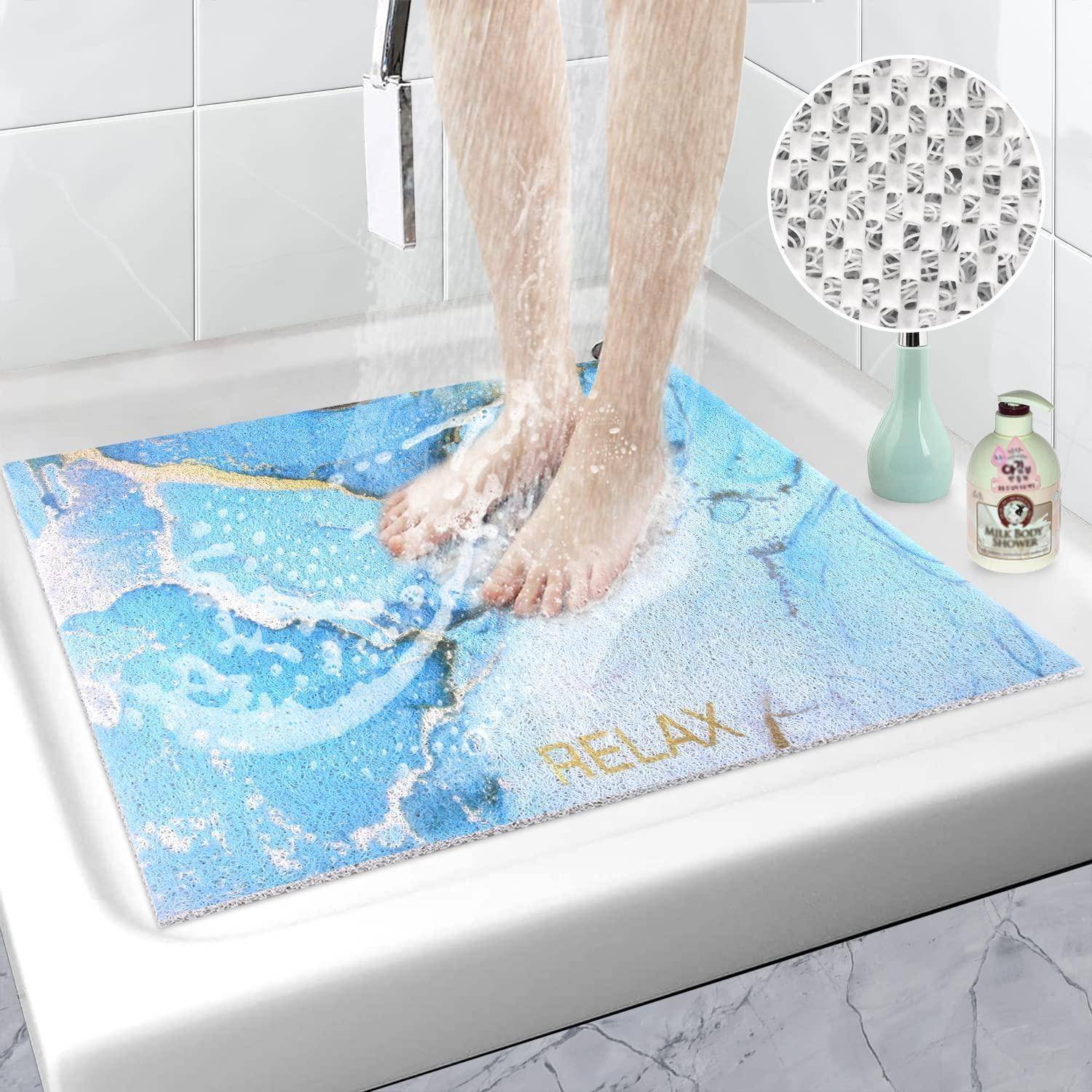 Person, die in einer Dusche auf einer blauen Badematte steht, die Wasser aufnimmt und eine rutschfeste Oberflächenstruktur hat.
