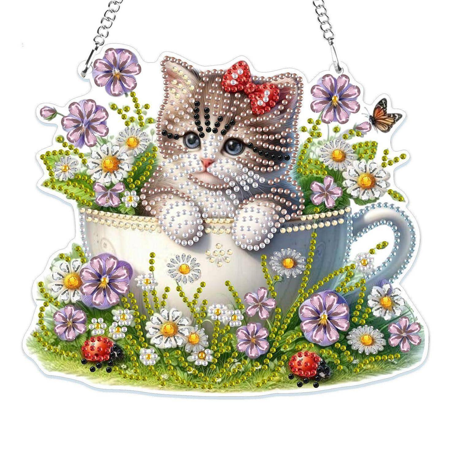 Dekoratives Kätzchen in einer Teetasse, umgeben von Blumen und Schmetterlingen, dargestellt als Perlenhandwerks-Ornament mit einer Hängekette.