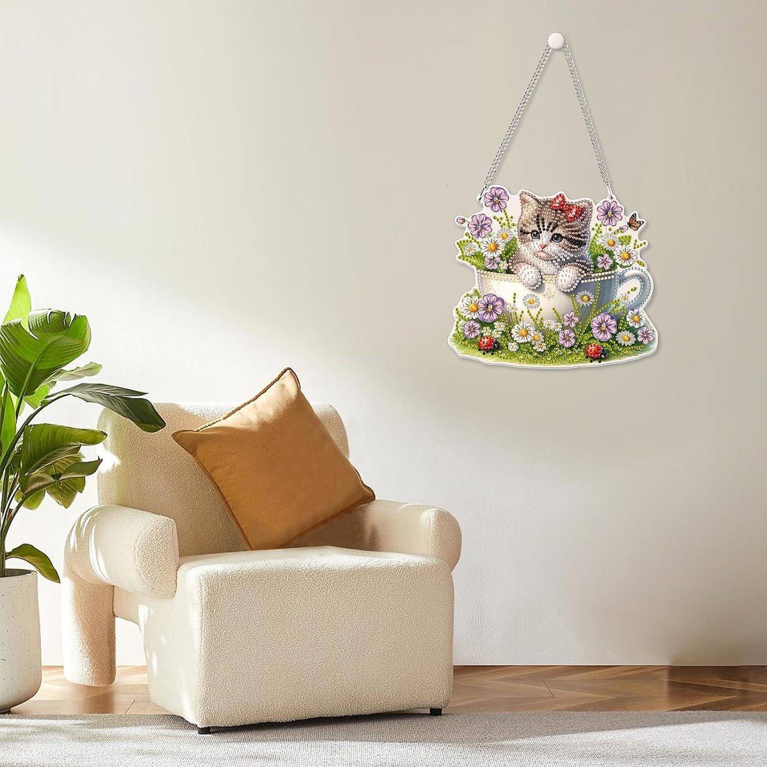 Cremeweißer Sessel mit beigem Kissen in einem hellen Zimmer neben einer Pflanze, mit einer hängenden Wanddekoration aus Blüten mit Katze in einer Teetasse.