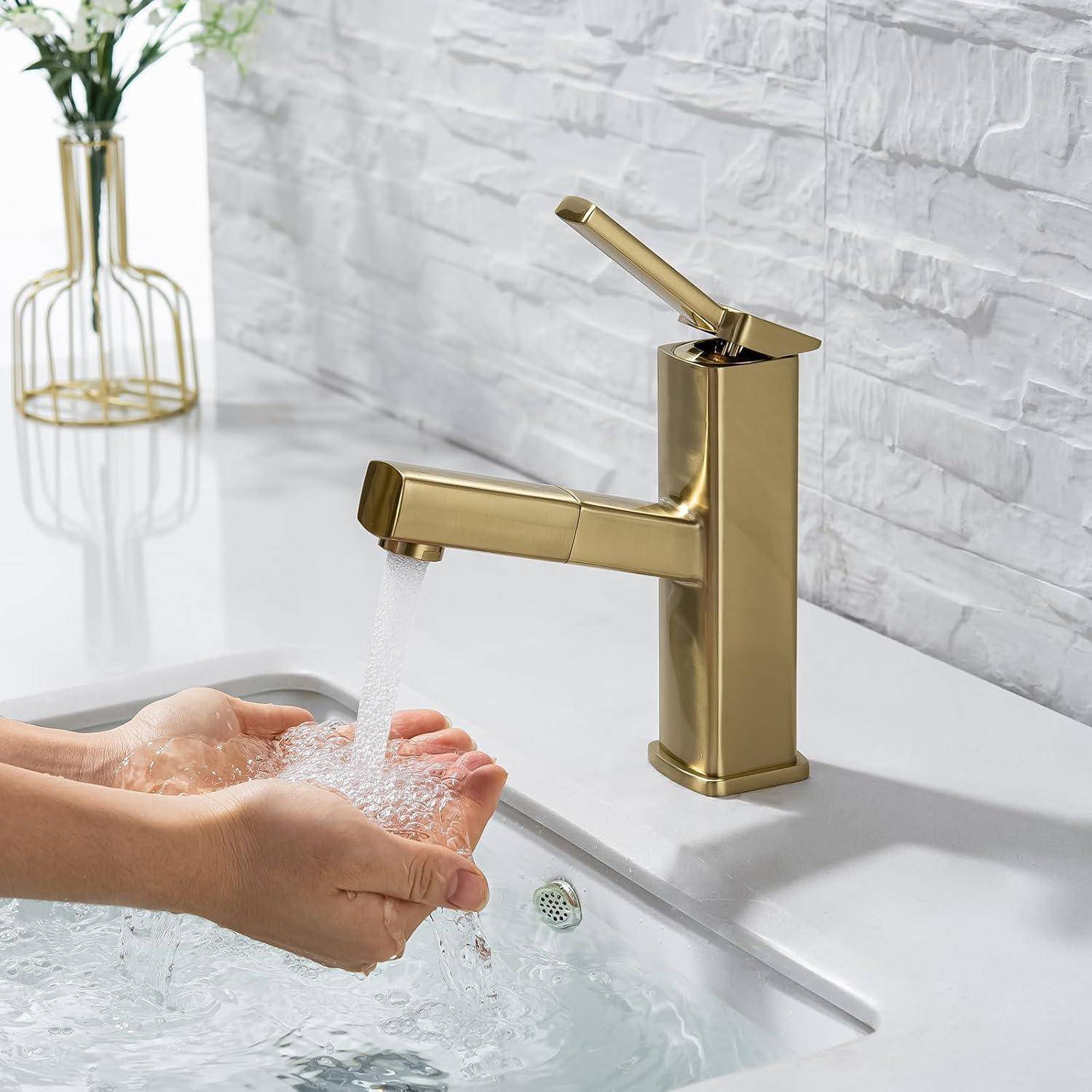 Hände werden unter fließendem Wasser aus einem vergoldeten Badezimmerhahn über einem Waschbecken gewaschen.