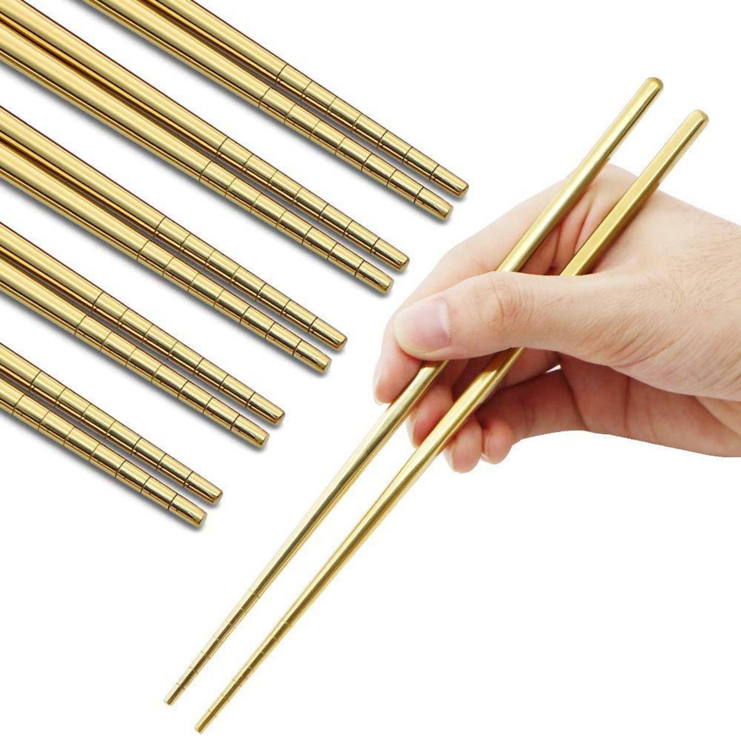 Eine Hand hält ein Paar goldfarben Stäbchen neben mehreren passenden Stäbchen, die diagonal auf weißem Hintergrund angeordnet sind.
