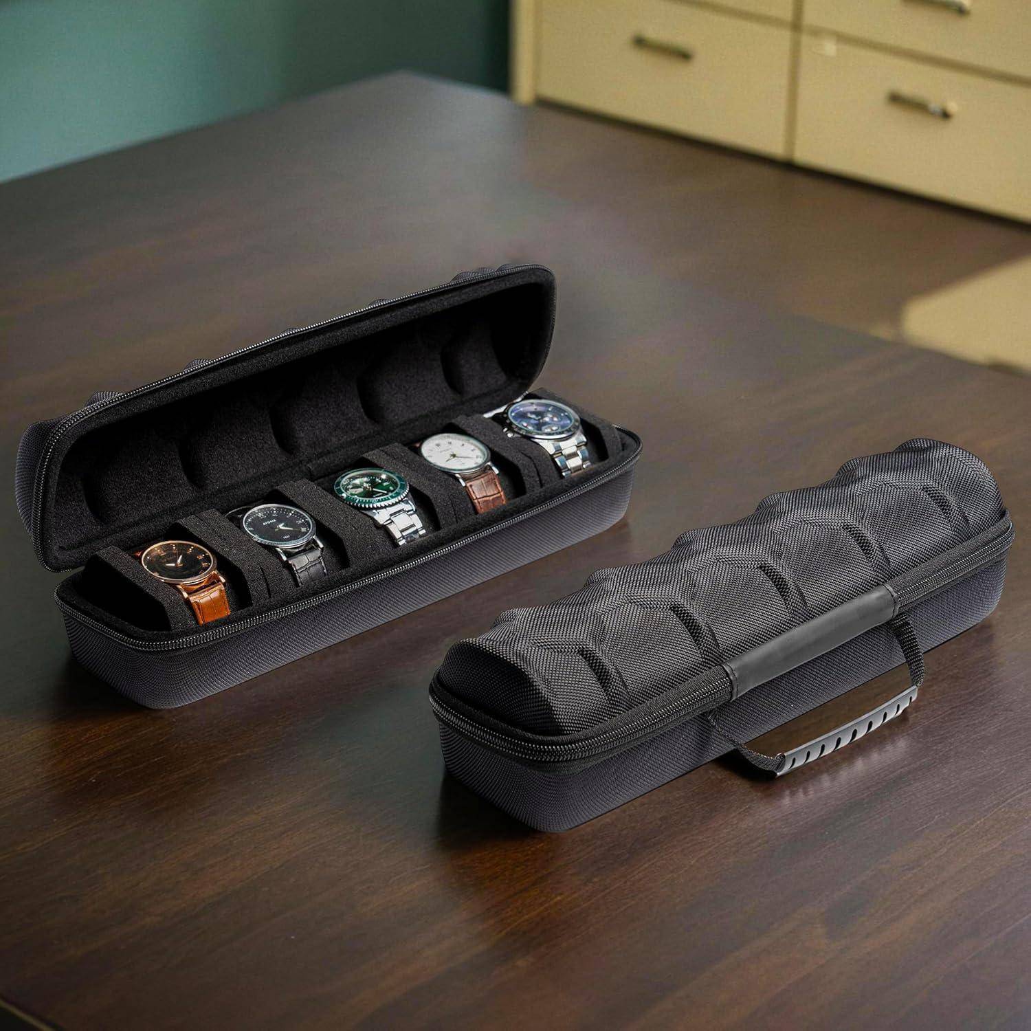 Offener schwarzer Uhrenkoffer mit Reißverschluss auf einem Tisch mit fünf Armbanduhren, neben einem geschlossenen passenden Reisekoffer.