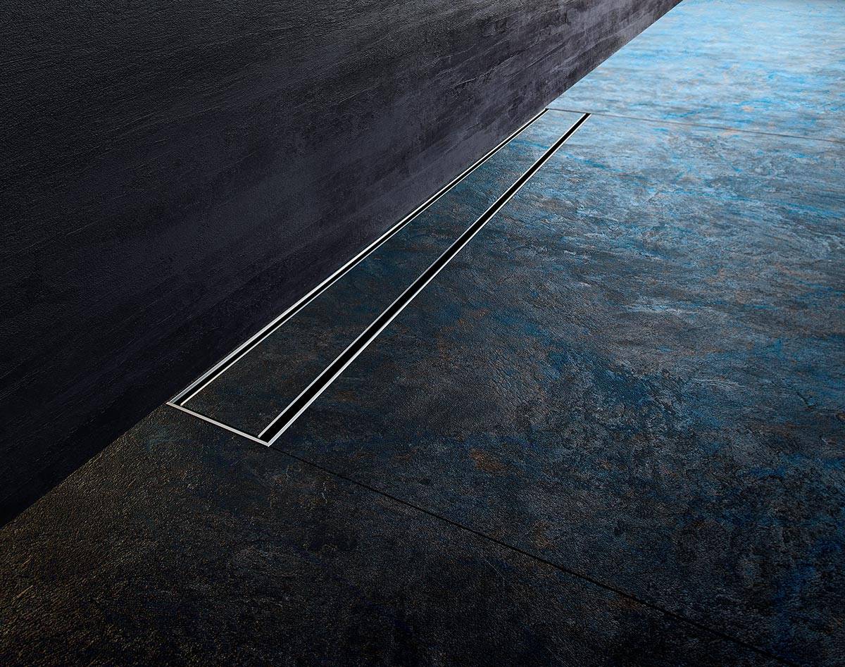Minimalistischer dunkler Boden mit einem langen, schmalen linearen Abfluss oder einer Vertiefung, die zu einer leuchtend blauen, wasserähnlichen Oberfläche führt.