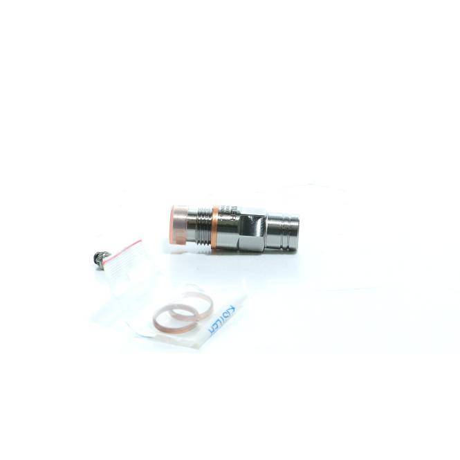 Kleiner Metallstecker oder Stecker auf einer weißen Oberfläche liegend, mit einem lockeren Draht und einer kleinen Dichtung oder einem Ring in der Nähe in einer Verpackung.