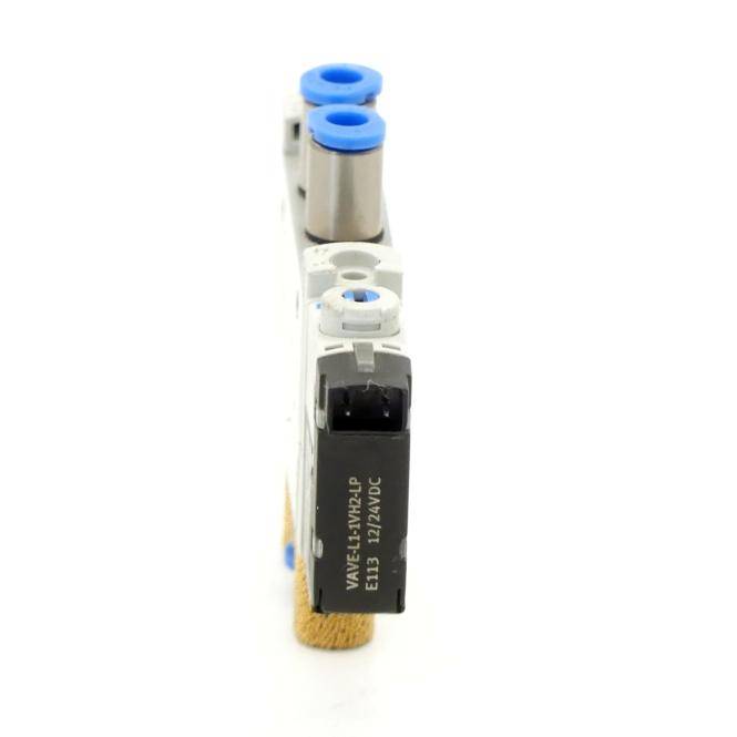 Nahaufnahme eines pneumatischen Magnetventil-Verteilers mit blauen Druckverbindungsfittings und einem schwarzen elektrischen Stecker auf weißer Grundplatte.