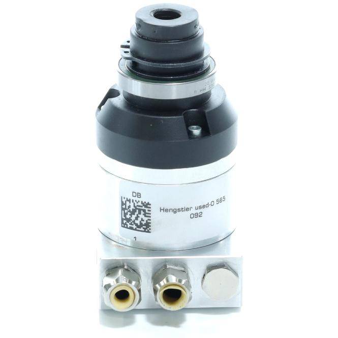 Nahaufnahme einer zylindrischen Industriekomponente mit zwei Gewindelöchern und einem aufgedruckten Etikett, wahrscheinlich ein Hydraulik- oder Pneumatikventil.