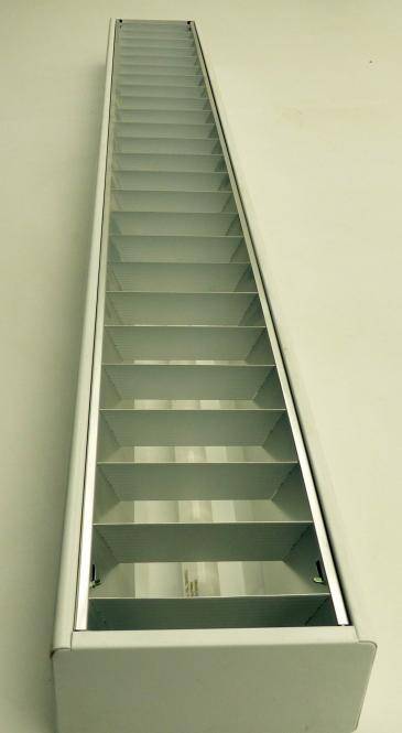 Lange, schmale Metalltreppe oder Leiter, die steil nach oben in einem schlichten Schacht im Inneren führt, von unten betrachtet.