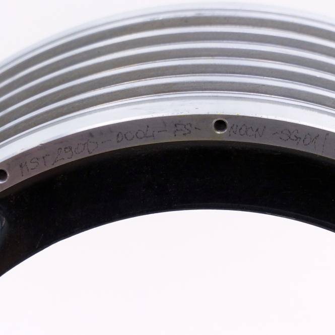 Nahaufnahme eines metallischen kreisförmigen Rings oder Lagers mit eingravierten Markierungen und einem zentralen Loch, vor einem schlichten hellen Hintergrund fotografiert.