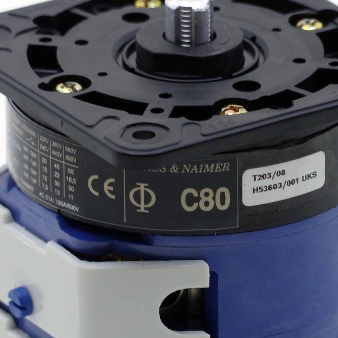 Nahaufnahme einer schwarzen und blauen Elektromaschine oder eines Zahnradkomponentes mit einer zentralen Welle und Beschriftungsmarkierungen.