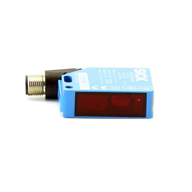 Blauer rechteckiger Industrie-Sensor mit gewindefähigem Metallstecker und roter Frontlinse, dargestellt auf weißem Hintergrund.