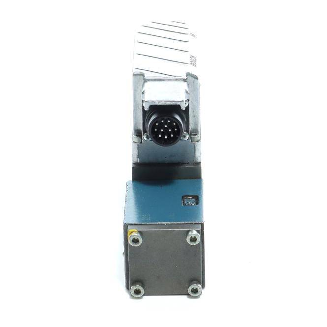 Nahaufnahme eines kleinen industriellen Elektrosteckers oder Sensormoduls mit einem kreisförmigen Mehrkanal-Anschluss auf einem blau-grauen Metallgehäuse.
