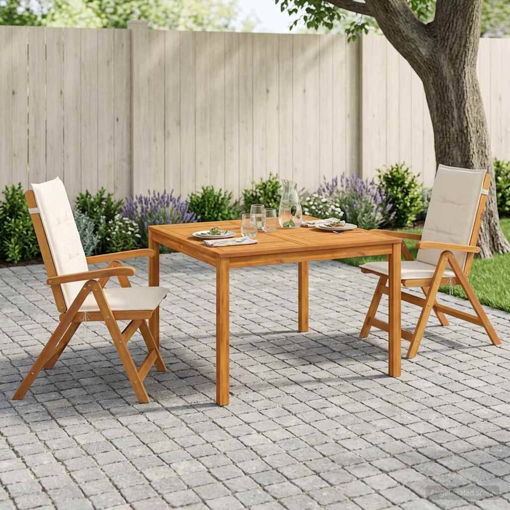 Gartenmöbelset für den Außenbereich mit einem Holztisch und zwei gepolsterten Stühlen auf einem gepflasterten Steinplatz neben einem Baum und einem Zaun.
