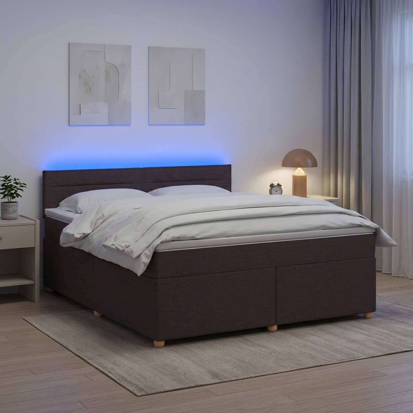 Modernes Schlafzimmer mit dunkel gepolstertem Bett, weißer Bettwäsche, blauem hinterleuchtetem Kopfteil, Nachttischlampe, Wandkunst, Teppich und transparenten Vorhängen.