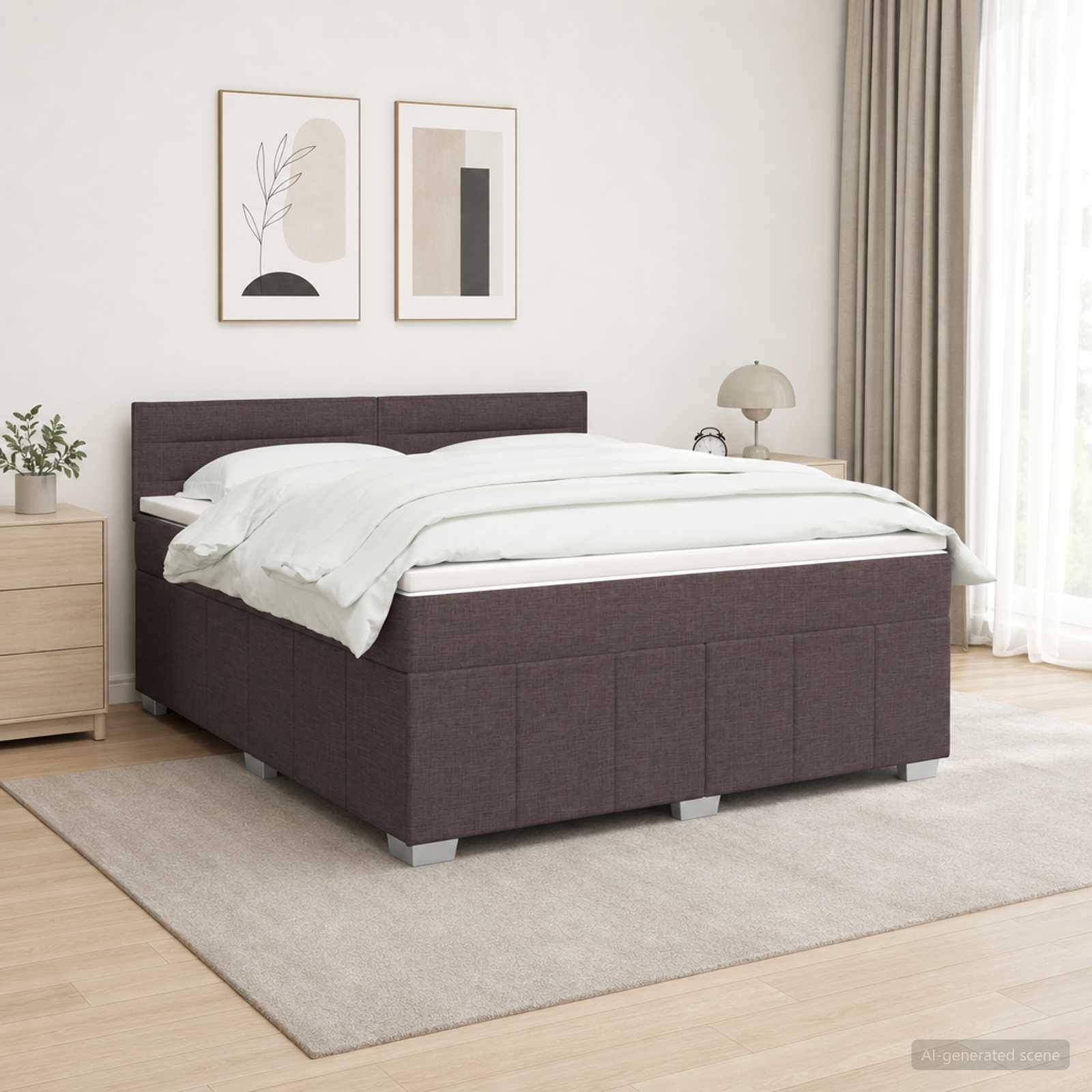 Modernes Schlafzimmer mit dunkel gepolstertem Bett, weißer Bettwäsche, zwei gerahmten Wanddrucken, Nachttisch, Lampe und beigem Teppich.