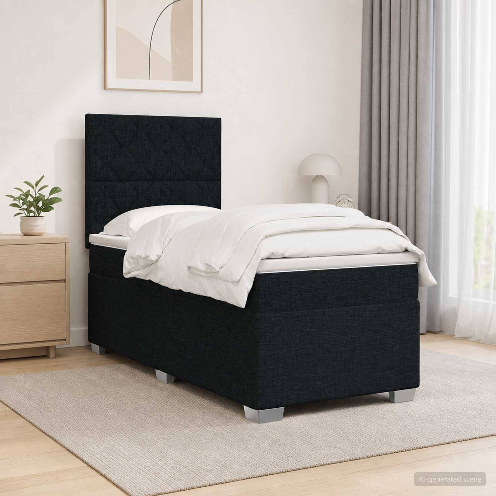 Schwarzes gepolstertes Einzelbett mit weißer Bettwäsche in einem minimalistischen Schlafzimmer, neben einem hölzernen Nachttisch und einer Lampe auf einem beigefarbenen Teppich.