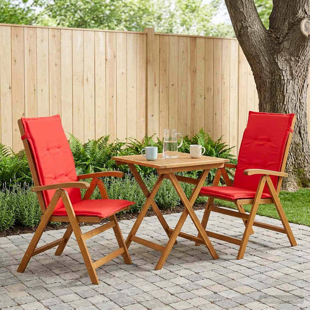 Sitzbereich auf der Terrasse mit zwei roten gepolsterten Holzstühlen und einem kleinen Tisch, auf dem sich ein Krug und Becher befinden, neben einem Baum und einem Holzzaun.