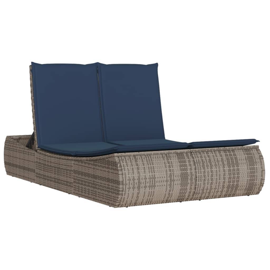 Geflochtene Outdoor-Liegestuhl mit blauen Kissen, in zusammengeklappter aufrechter Position gezeigt.