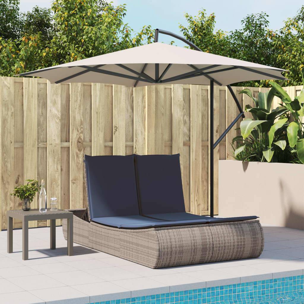 Externe Liegestuhl mit Sonnenschirm neben einem kleinen Beistelltisch und einem eingezäunten Garten.