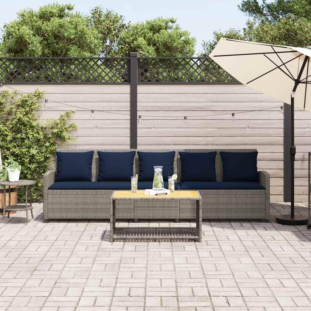 Outdoor-Terrasse mit Korbsofa, Couchtisch und Sonnenschirm vor einem Sichtschutzzaun, zeigt einen gestalteten Sitzbereich.