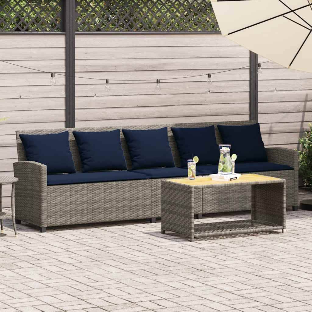 Outdoor-Terrassenmöbel-Set mit grauem Rattan-Sofa, marineblauen Kissen und passendem Couchtisch unter einem Sonnenschirm, vor einem Holzzaun aufgestellt.