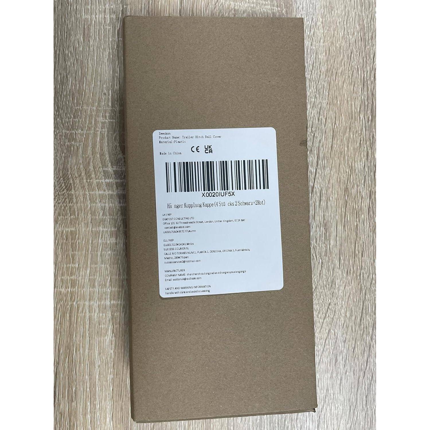 Ein einfacher brauner Karton mit einem weißen Produktetikett und einem Barcode liegt auf einem hellbraunen Holzboden.