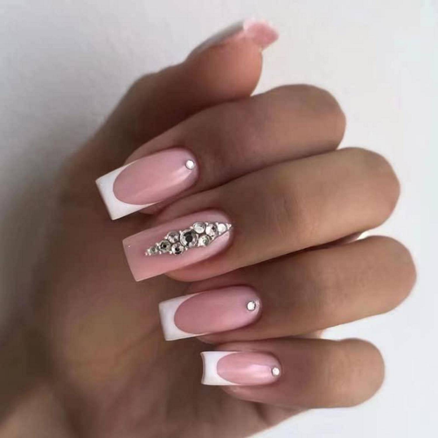 Hand mit rosa und weiß französischen Spitzennägeln, wobei ein Akzent-Nagel mit silbernen Strasssteinen verziert ist.
