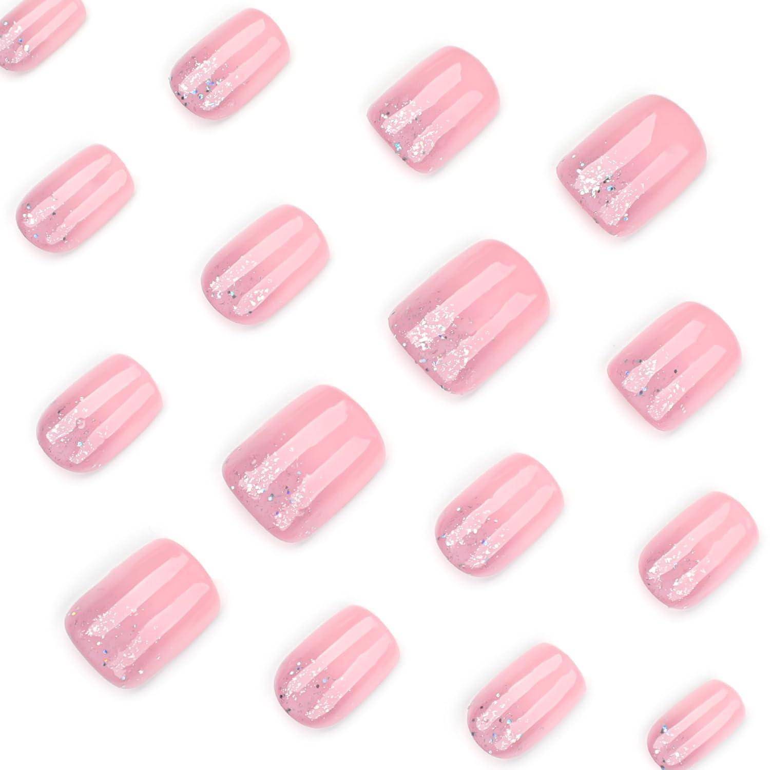 Muster aus rosa glänzenden künstlichen Nägeln mit Glitterakzenten, diagonal auf weißem Hintergrund angeordnet.