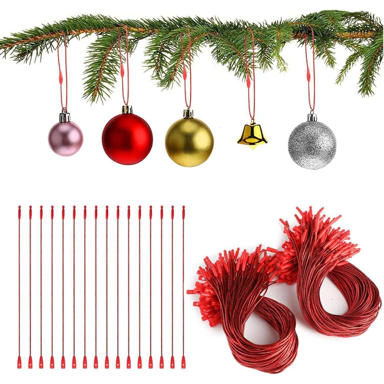 Weihnachtsgirlande mit hängenden Ornamenten, roten Lichterketten und aufgerollten roten Drähten auf weißem Hintergrund.