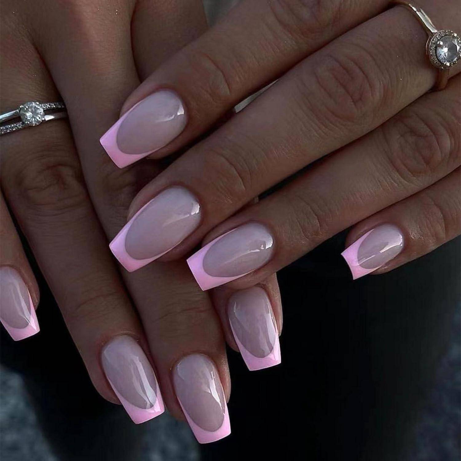 Nahaufnahme von Händen mit glänzender rosa French Manicure und silbernen Ringen.