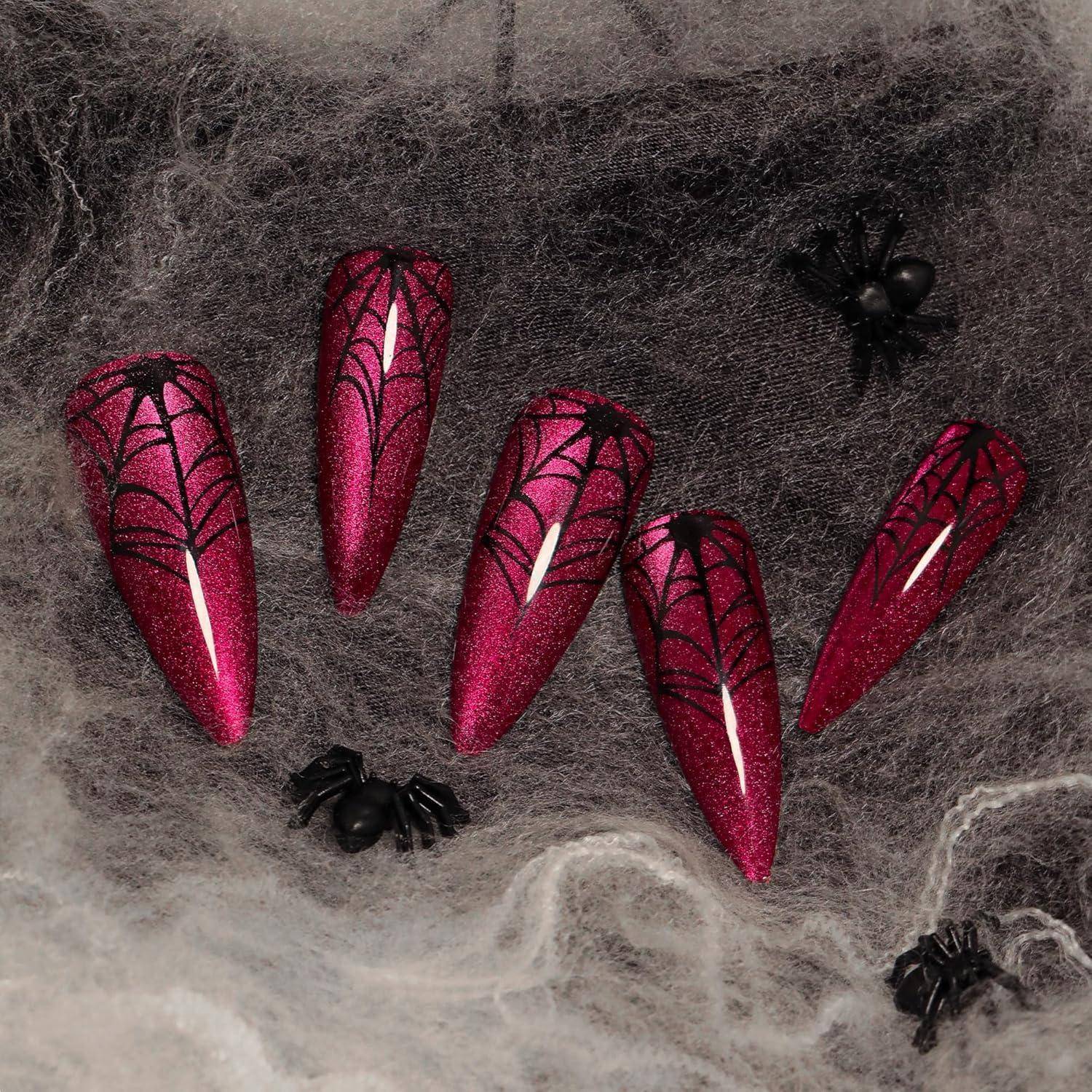 Fünf magentafarbene Spinnennetz-Nagelspitzen arrangiert auf grauem Spinnennetz-Hintergrund mit kleinen schwarzen Spinnen.