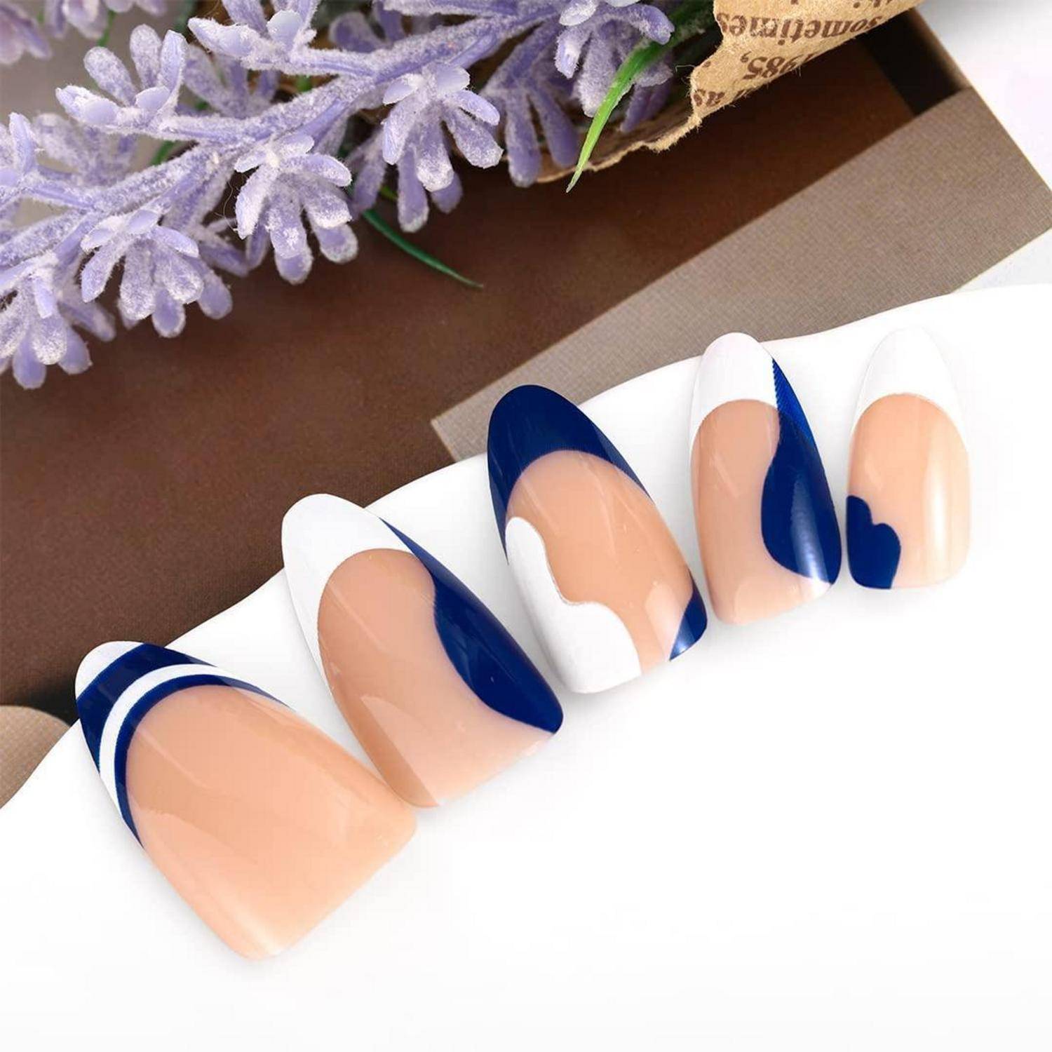 Vier künstliche Nägel mit nackten, weißen und marineblau abstrakten geometrischen Designs auf einer weißen Oberfläche angezeigt.