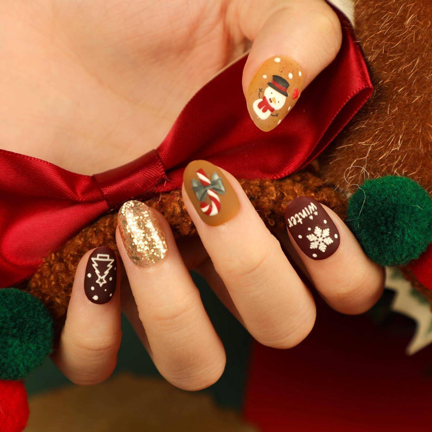 Hand mit festlicher Weihnachts-Nagelkunst, die ein rotes Band hält, mit Schneemann, Zuckerstange, Glitter, Baum und 