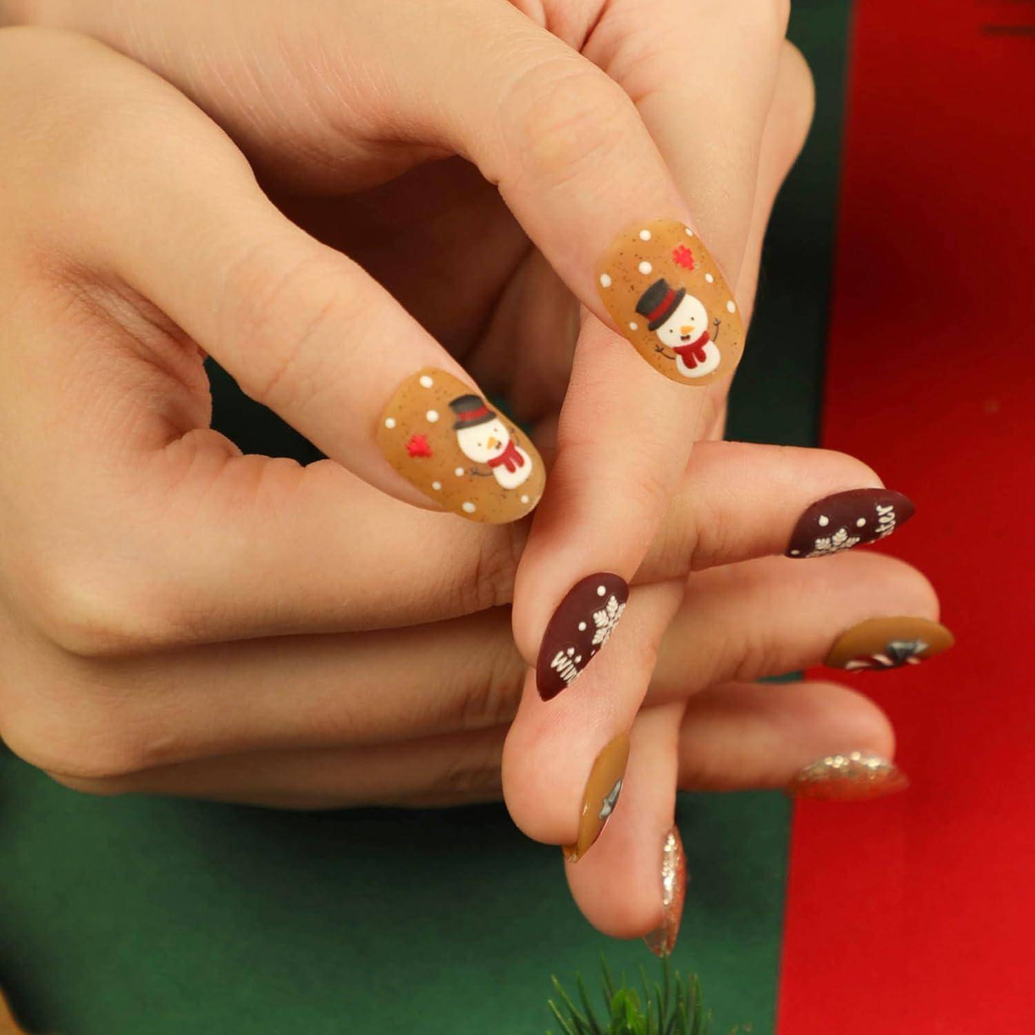 Nahaufnahme von Händen mit festlicher Weihnachts-Nagelkunst mit Schneemännchen, Schneeflocken und Glitter auf braunen und burgunderfarbenen Nägeln.