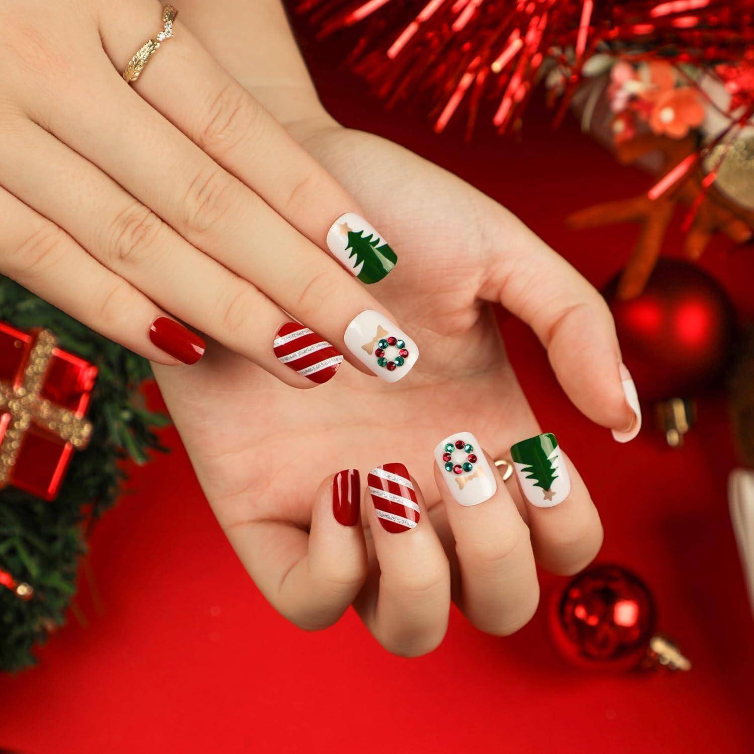 Nahaufnahme von Händen mit weihnachtlichem Nagellack in Rot, Grün und Weiß mit Nagelkunst-Designs, einschließlich Zuckerstangen-Streifen, Bäumen und Schneeflocken-Mustern.
