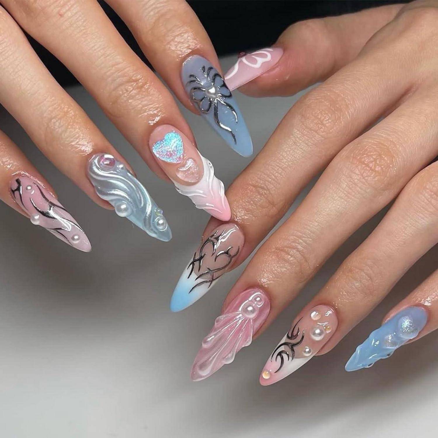 Nahaufnahme von zwei Händen mit langen, spitz zulaufenden pastellfarbenen Acrylnägeln mit 3D-Blüten- und Wirbelmusterdetails in Rosa, Blau, Silber und Weiß.