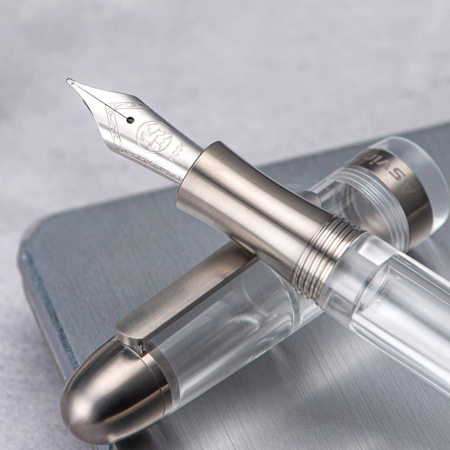 Nahaufnahme von zwei Füllfederhaltern auf einer grauen Oberfläche, ein transparenter Stift mit einer silbernen Feder, der über einen verschlossenen metallischen Stift gekreuzt ist.