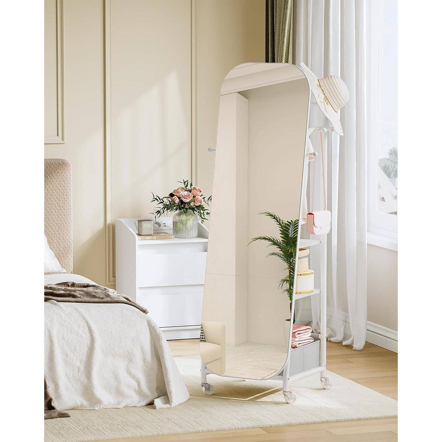 Ganzseitiger weißer Standspiegel mit integrierten Seitenregalen in einem hellen Schlafzimmer, neben einem Bett, einer Kommode und einem Fenster.