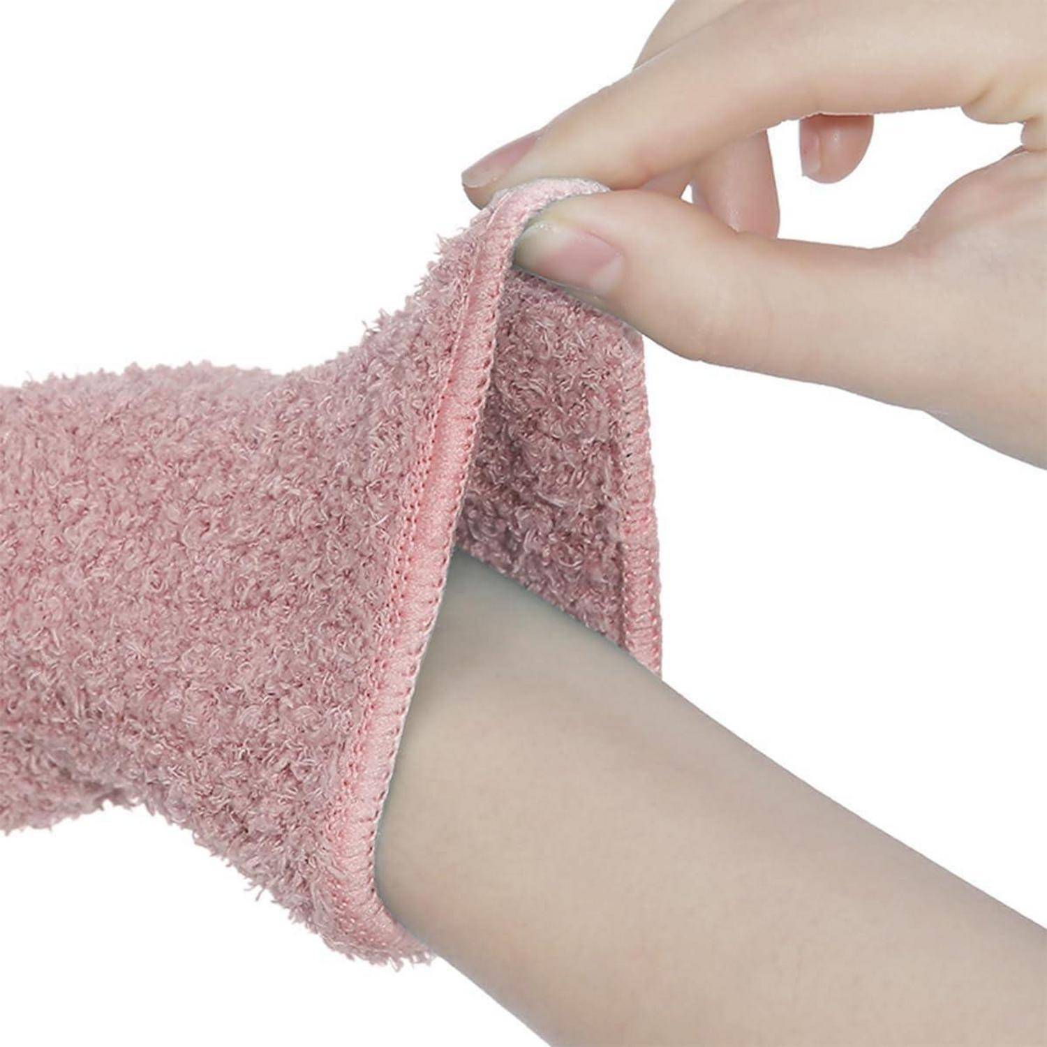 Nahaufnahme einer Hand, die einen rosa Frottee-Ärmel über einen Arm hochzieht, wobei die Manschette und die weiche Stofftextur sichtbar sind.
