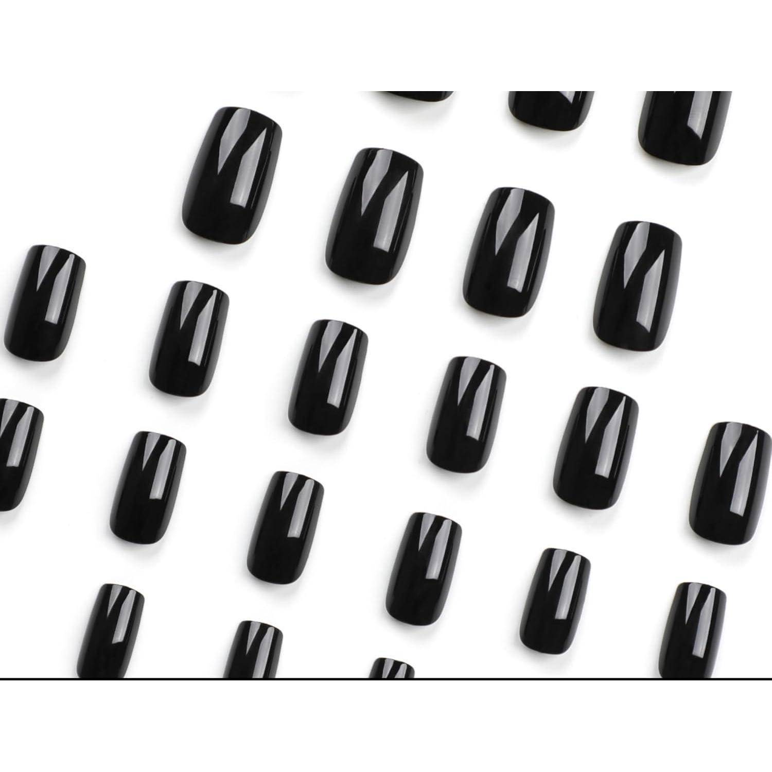 Schwarze glänzende künstliche Nagelspitzen diagonal auf weißem Hintergrund angeordnet.