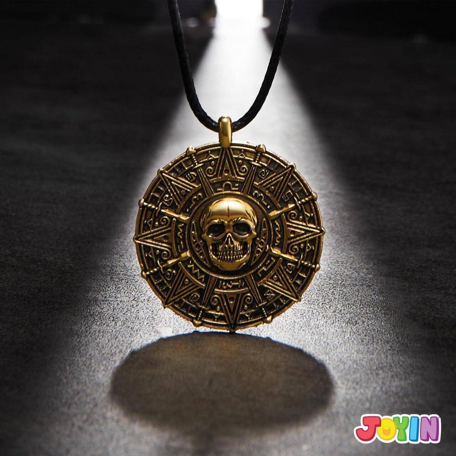 Goldener Totenschädel-Anhänger an einer schwarzen Schnur, zentriert auf einer dunklen Oberfläche mit Scheinwerferlicht und Schatten.