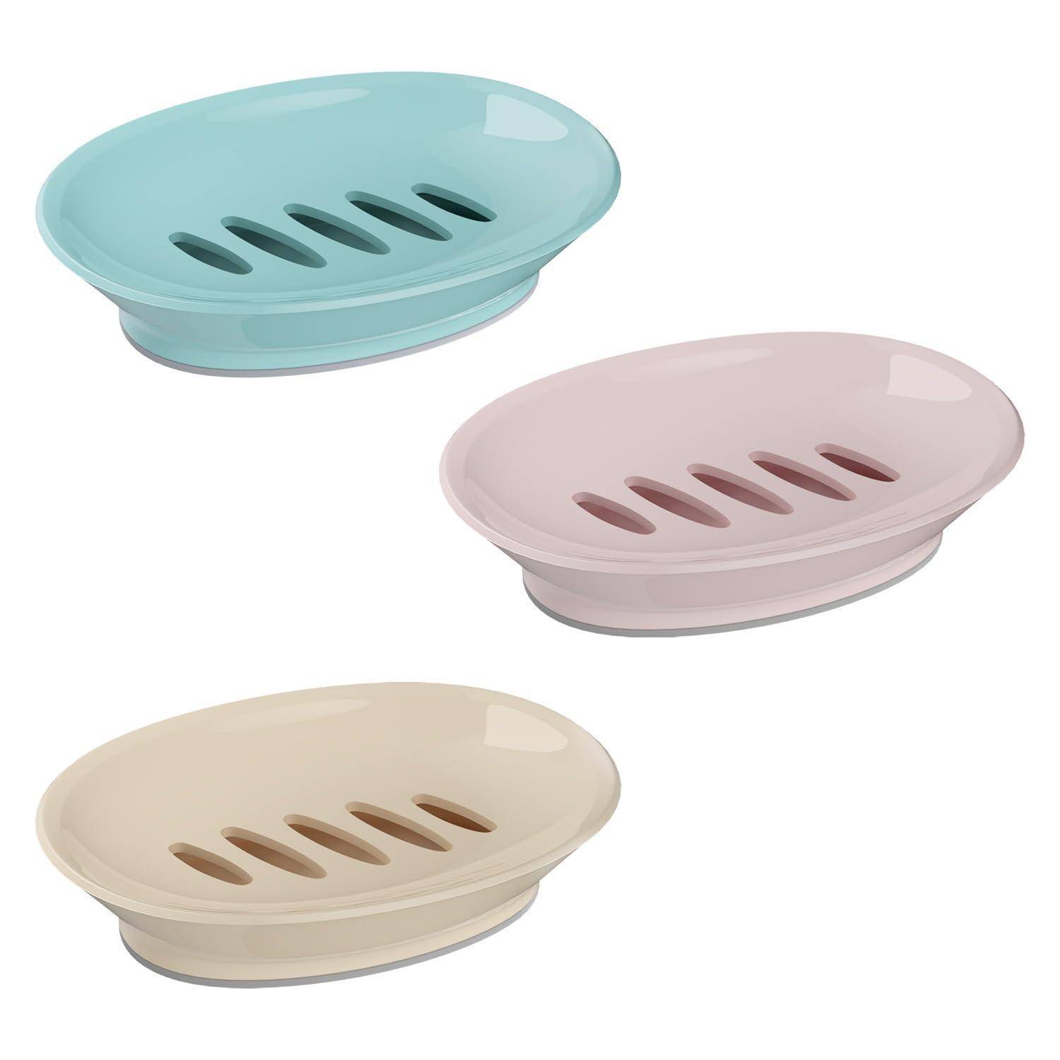 Drei ovale Seifenschalen in Blau, Rosa und Beige, jeweils mit Ablaufschlitzen und erhöhtem Boden.