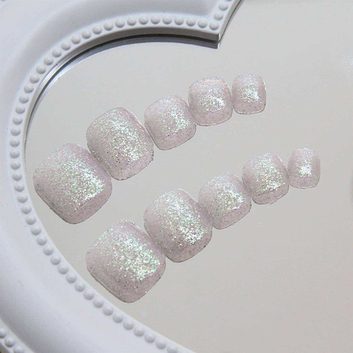 Set aus funkelnden hellrosa Glitter-Kunstzehennägeln, angeordnet in zwei gebogenen Reihen auf einem weißen Display-Rahmen.