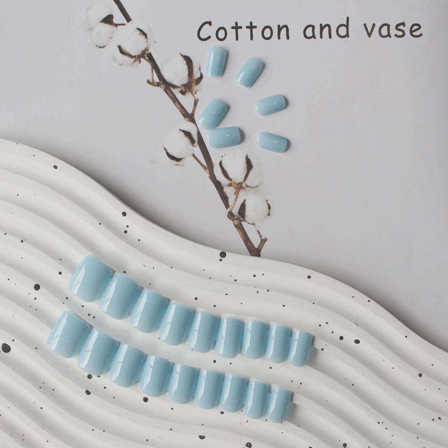 Ein Nagelkunstdesign auf weißem welligem Hintergrund, mit hellblauen glänzenden Nägeln, die wie Baumwollblütenblätter angeordnet sind, und dem Text „Cotton and vase