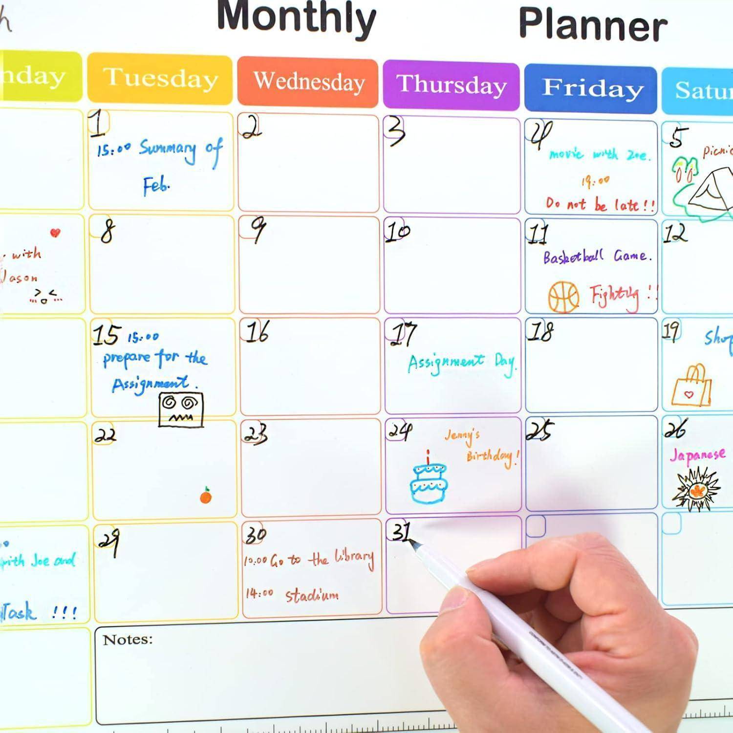 Eine Hand schreibt in einen bunten Monatsplaner-Kalender mit datierten Feldern und Notizen für Aufgaben, Ereignisse und Erinnerungen.