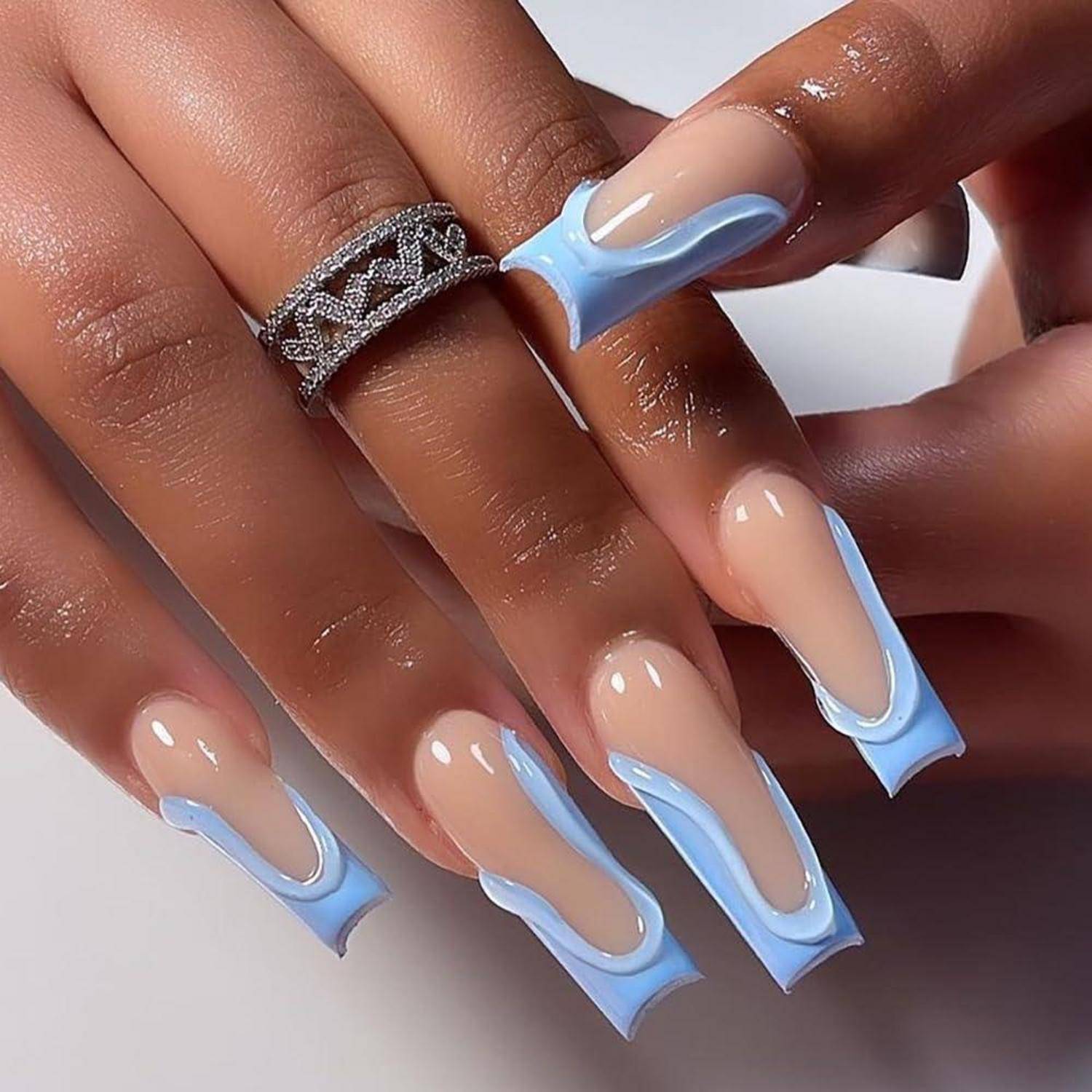 Nahaufnahme von Händen mit langen Nägeln im Nude-und-Hellblau-Französisch-Manikür-Stil und einem silbernen Ring an einem Finger.
